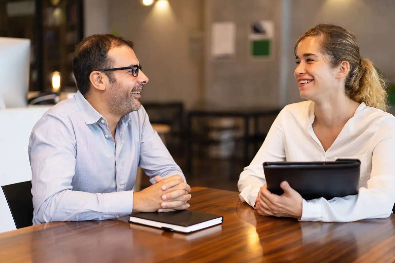 Happy middle-aged manager speaking with a young female client.